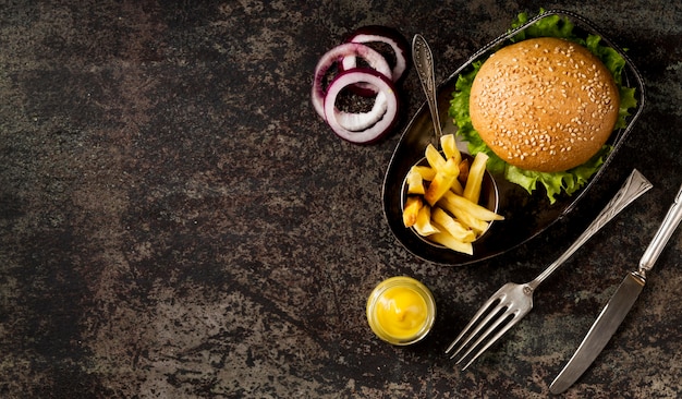 Foto gratuita vista superior de hamburguesas y papas fritas con cubiertos y espacio de copia