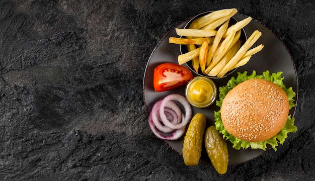 Vista superior de hamburguesas y papas fritas en un plato con encurtidos y espacio de copia