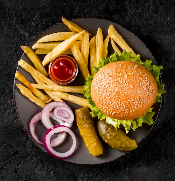 Vista superior de hamburguesas y papas fritas en un plato con encurtidos