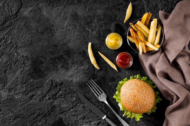 Vista superior de hamburguesas y papas fritas con salsas y espacio de copia