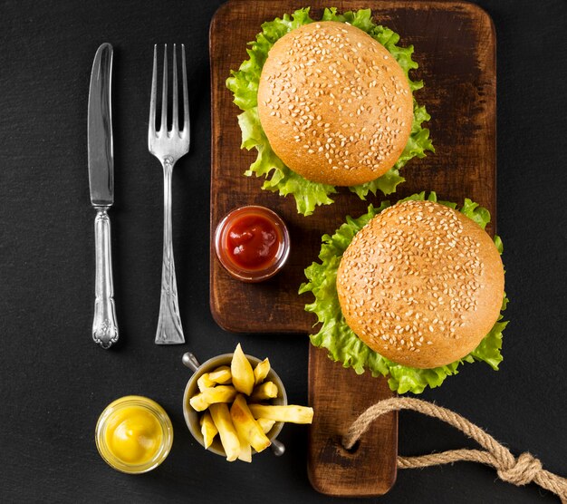 Vista superior de hamburguesas y papas fritas en tabla de cortar