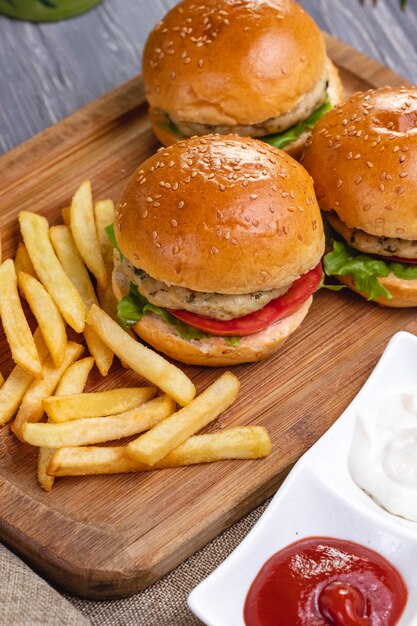 Vista superior hamburguesas de pollo con papas fritas ketchup y mayonesa en el tablero