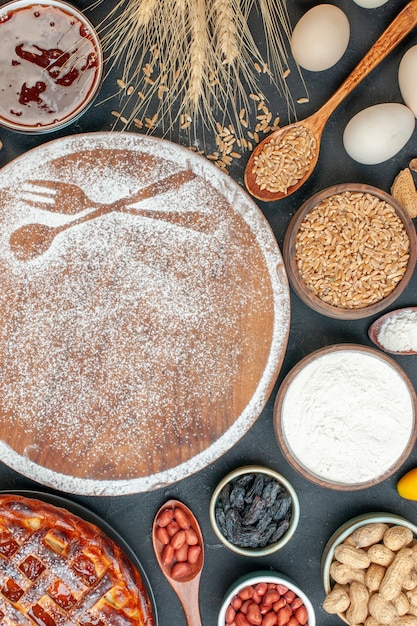 Foto gratuita vista superior de harina blanca en forma de tenedor y cuchara con huevos y nueces en pastel oscuro, galleta dulce, azúcar, pastelería, té de tarta