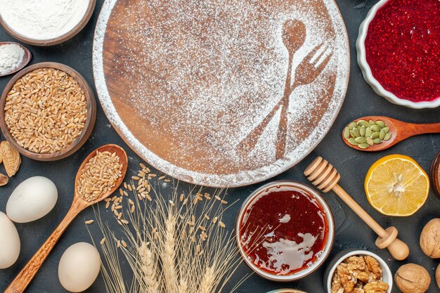 Vista superior de harina blanca en forma de tenedor y cuchara con huevos y nueces en un pastel oscuro postre dulce galleta azúcar pastelería pastel té