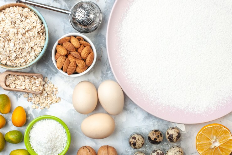 Foto gratuito vista superior de harina en polvo en tazones de fuente con harina, avena y almendras, nueces, huevos de codorniz, rodaja de limón en la mesa