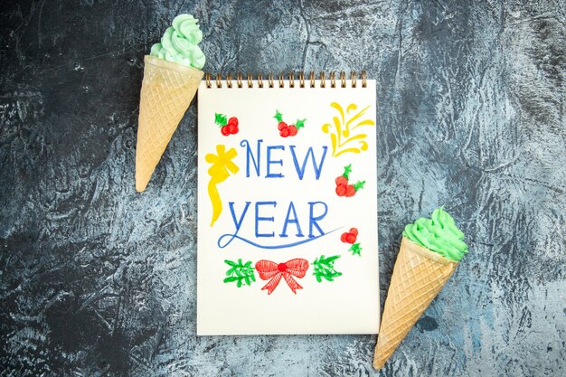 Vista superior helados año nuevo escrito en cuaderno sobre fondo gris