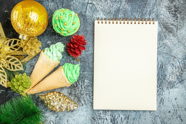 Vista superior helados árbol de navidad cupcake adornos navideños cuaderno sobre fondo gris