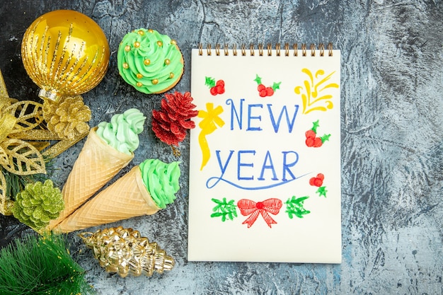 Foto gratuita vista superior de helados de navidad con año nuevo escrito en un cuaderno sobre fondo gris