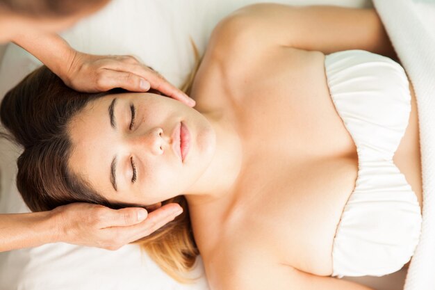 Vista superior de una hermosa joven hispana equilibrando su energía en una sesión de reiki en una clínica de salud y spa