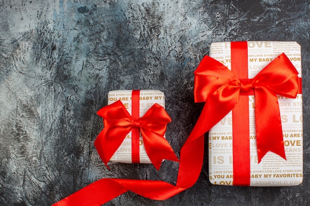 Vista superior de hermosas cajas de regalo atadas con cinta roja en diferentes tamaños sobre fondo oscuro helado