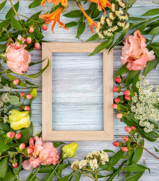 Vista superior de hermosas y coloridas flores con hojas en madera gris con espacio de copia