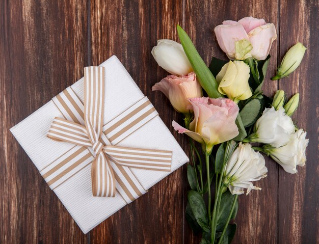 Vista superior de hermosas flores como tulipán y rosas con caja de regalo aislada sobre un fondo de madera