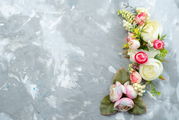 Una vista superior de hermosas flores con hojas en un escritorio brillante, color de plantas de flores