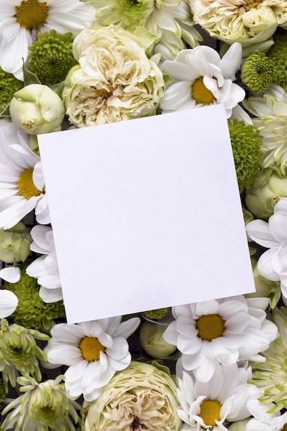 Vista superior de hermosas flores con tarjeta en blanco