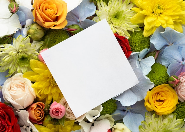 Vista superior de hermosas flores con tarjeta en blanco