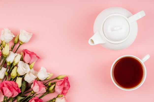 Vista superior hermoso arreglo de rosas con tetera y taza de té