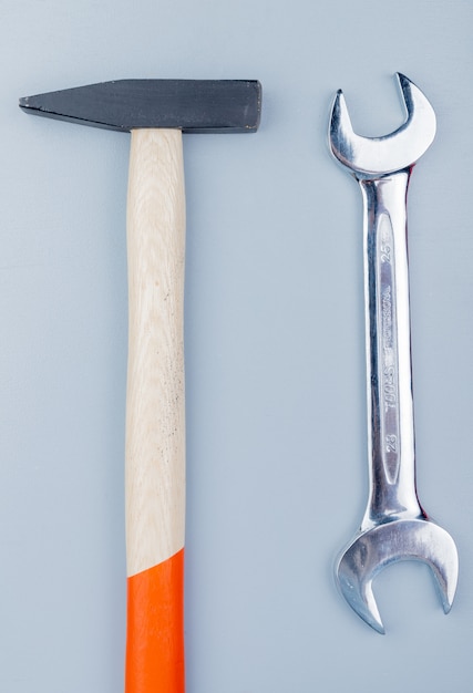 Vista superior de herramientas de construcción como martillo de ladrillo y llave de boca sobre fondo gris