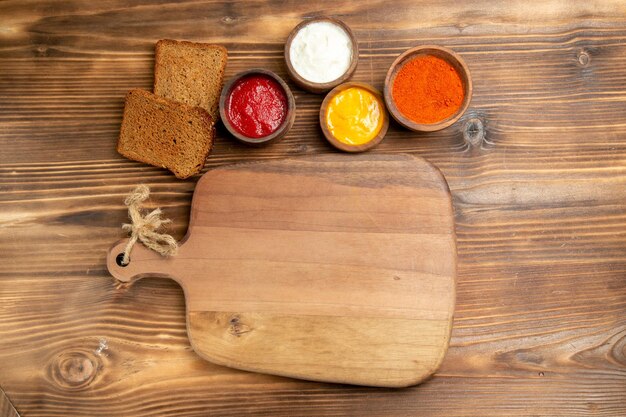 Vista superior de hogazas de pan oscuro con condimentos en la mesa de madera marrón comida pan bollo condimento comida