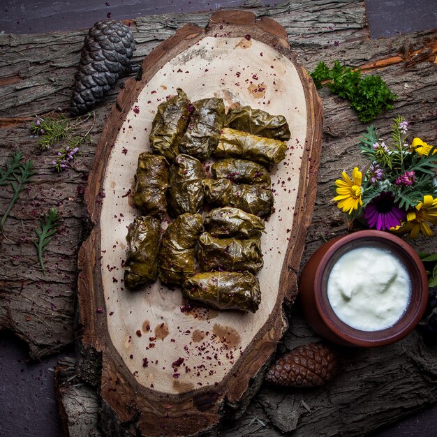 Vista superior hojas de uva dolma rellenas de carne y arroz con salsa de crema agria. cocina tradicional de europa oriental y asiática