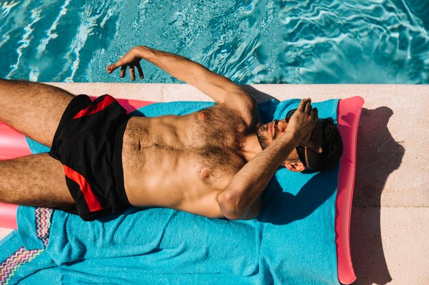 Vista superior de hombre relajando al lado de piscina
