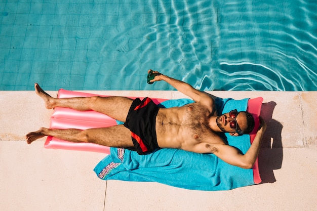 Vista superior de hombre relajando al lado de piscina