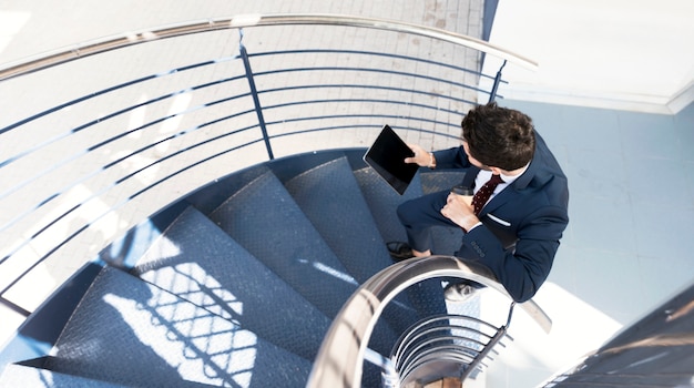 Vista superior hombre con tableta de pie en las escaleras