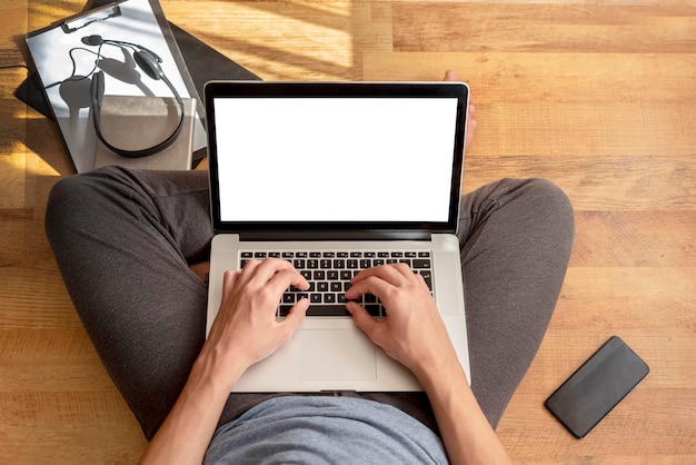Vista superior del hombre usando la computadora portátil en casa en cuarentena para trabajar