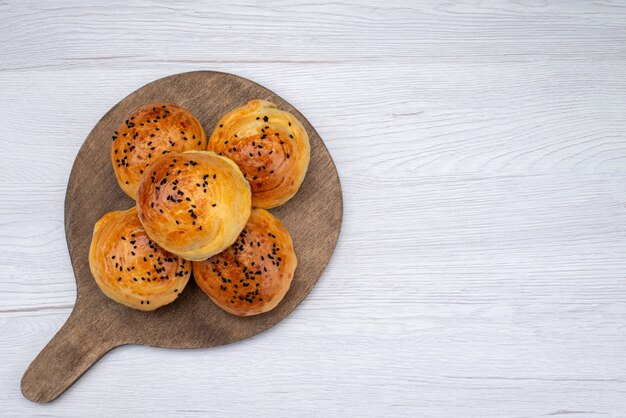 Vista superior horneados bollos sabrosos en el escritorio de madera y comida de pan de pan de fondo claro