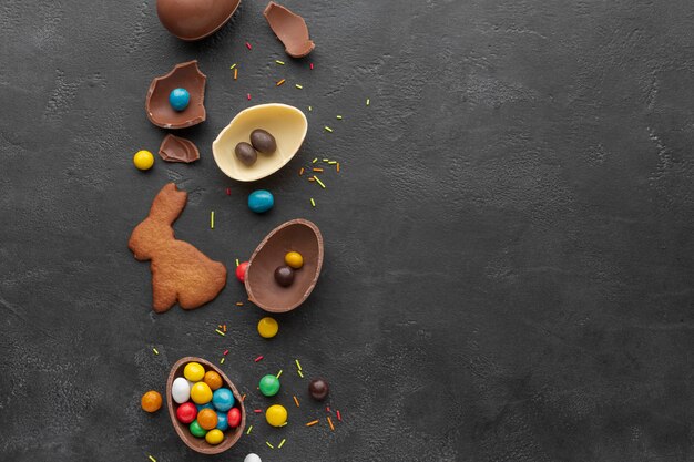 Vista superior del huevo de pascua de chocolate con dulces y galletas en forma de conejito