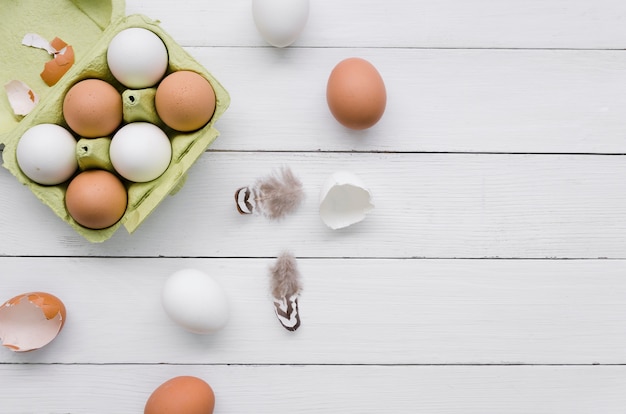 Vista superior de huevos en cartón para pascua con plumas y espacio de copia