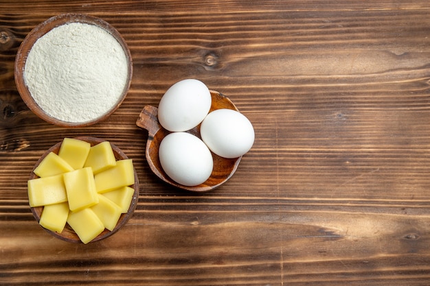 Foto gratuita vista superior de huevos crudos enteros con harina y queso en el producto de polvo de harina de masa de huevo de mesa marrón