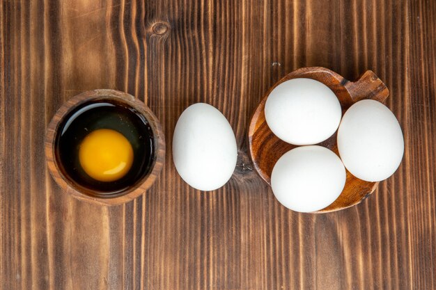 Vista superior de huevos crudos enteros en la superficie de madera marrón comida comida desayuno huevos de madera