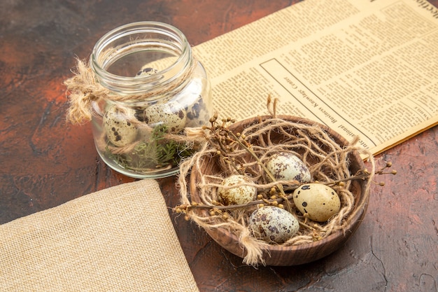 Vista superior de huevos frescos de granja en una olla de madera y en un vaso un bolso de periódico viejo sobre un fondo marrón