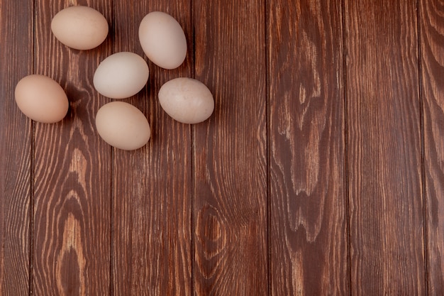 Vista superior de huevos frescos y ovalados sobre un fondo de madera con espacio de copia