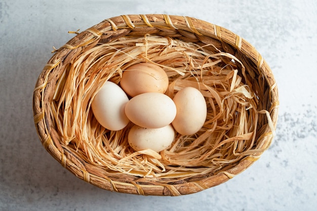 Foto gratuita vista superior de huevos de gallina orgánicos en canasta sobre superficie gris.