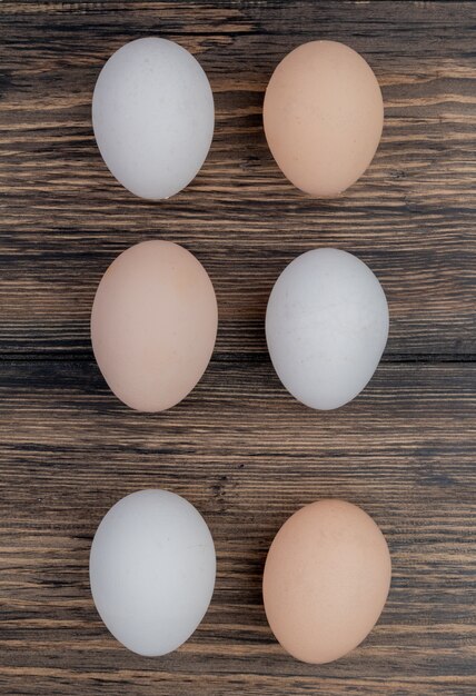 Vista superior de huevos de gallina sanos dispuestos en una línea sobre un fondo de madera