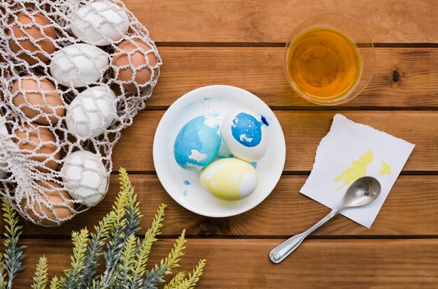 Vista superior de huevos de pascua en bolsa de malla con pintura y planta