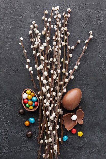 Vista superior de huevos de pascua de chocolate con dulces de colores dentro y flores