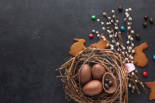 Vista superior de los huevos de pascua de chocolate en el nido con dulces y espacio de copia