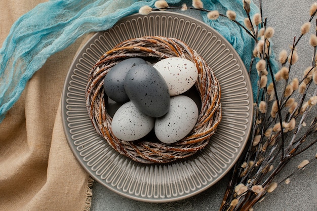 Vista superior de huevos de pascua de colores en la canasta en un plato con flores