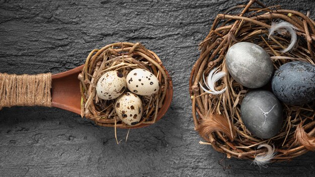 Vista superior de huevos de pascua en nido de pájaro hecho de ramitas y cuchara de madera
