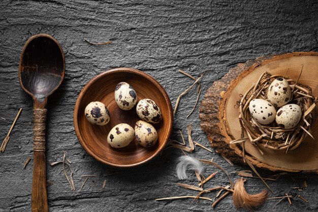 Vista superior de huevos de pascua en nido de pájaro y plato con cuchara de madera