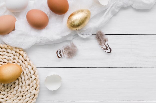 Vista superior de huevos de pascua con pintura dorada y plumas