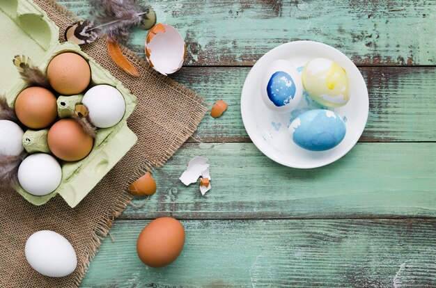 Vista superior de huevos pintados en un plato para pascua con plumas