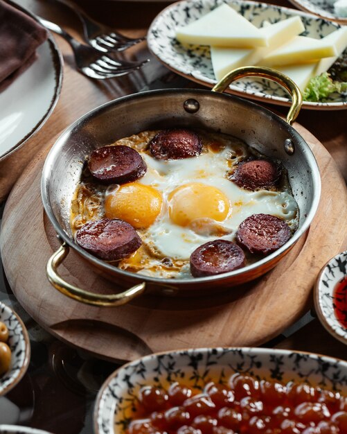 Una vista superior de huevos con salchichas junto con queso en el escritorio de madera marrón comida comida desayuno