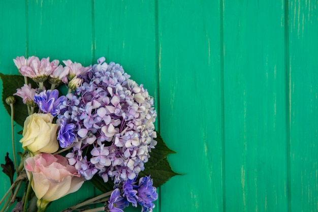 Vista superior de increíbles flores de colores como gardenzia daisy rose sobre un fondo de madera verde con espacio de copia