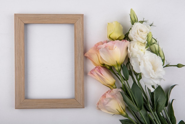 Vista superior de increíbles rosas blancas y amarillas con hojas sobre un fondo blanco con espacio de copia