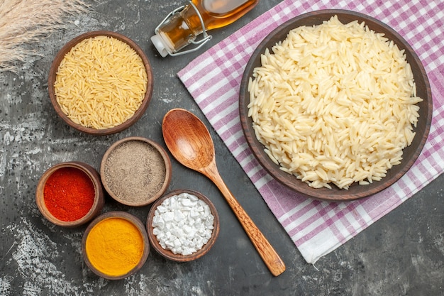 Foto gratuita vista superior del ión de arroz blanco cocido y hervido doblado toalla despojada púrpura botella de aceite caído diferentes especias y cuchara