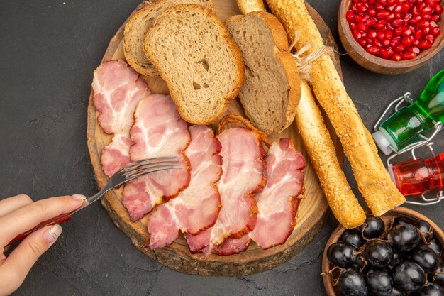 Vista superior de jamón fresco en rodajas con rebanadas de pan sobre fondo oscuro