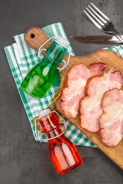 Vista superior de jamón fresco en rodajas sobre un escritorio de madera y fondo gris